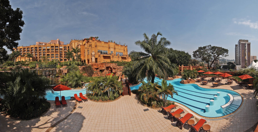 Trees in front of a pool of water with chairs by the side to relax