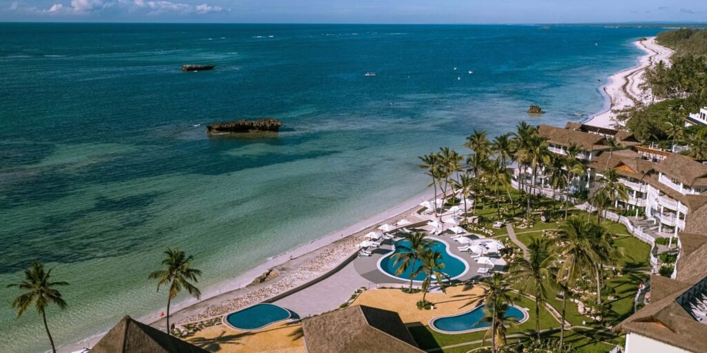 A beautiful beach with palm trees and pools in front